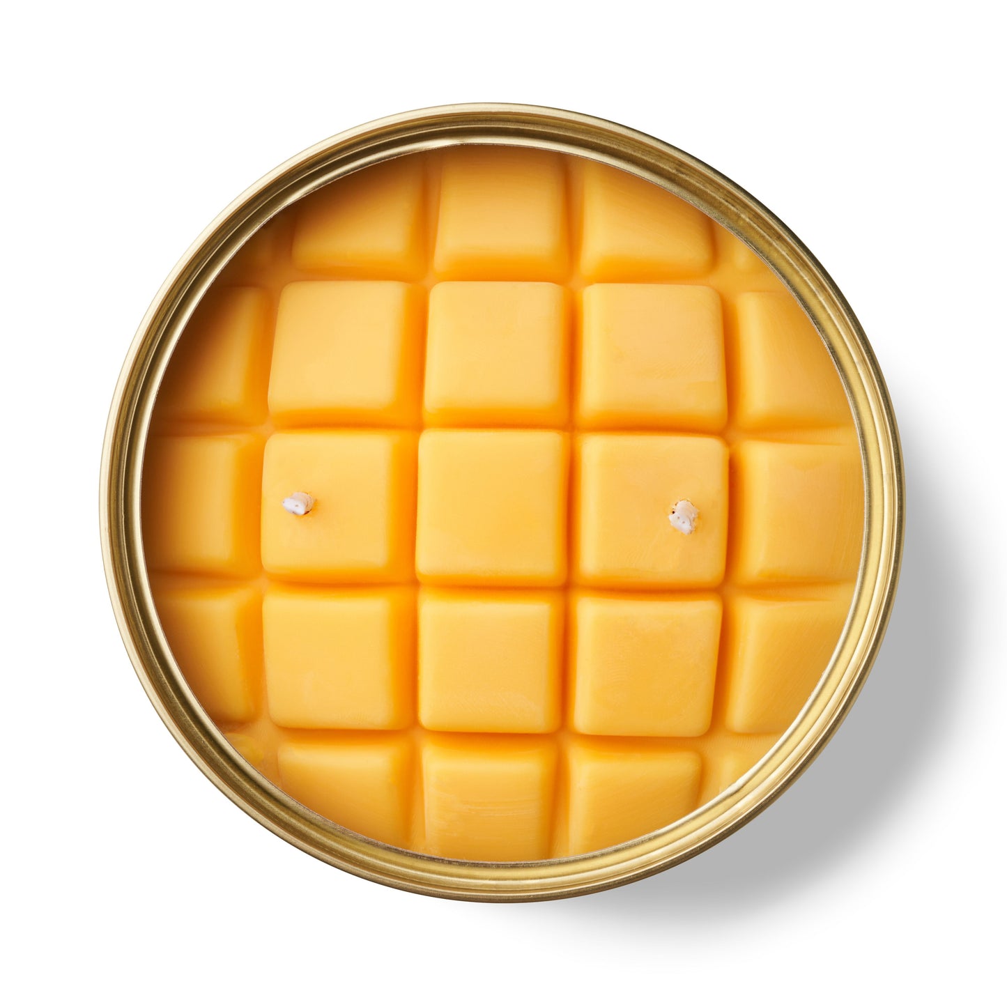 mango shaped candle in a gold tin on a white background